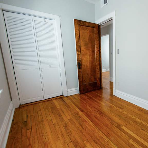 a bedroom with wood flooring and a door to a closet