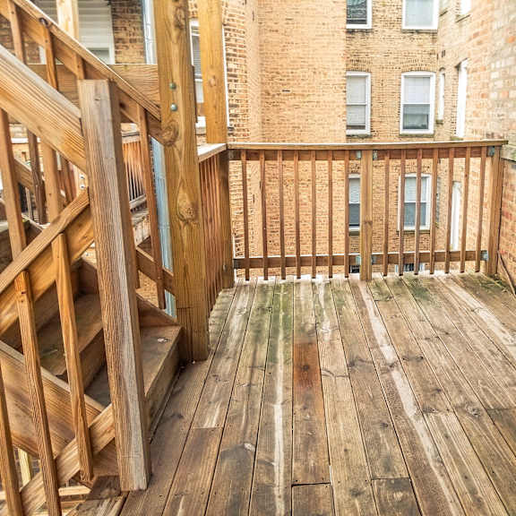 a balcony with wooden floors and a brick building in the background