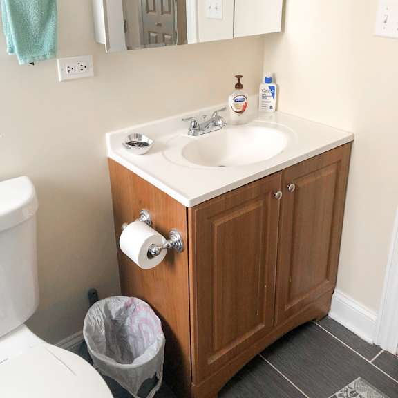 a bathroom with a toilet, sink, and mirror.