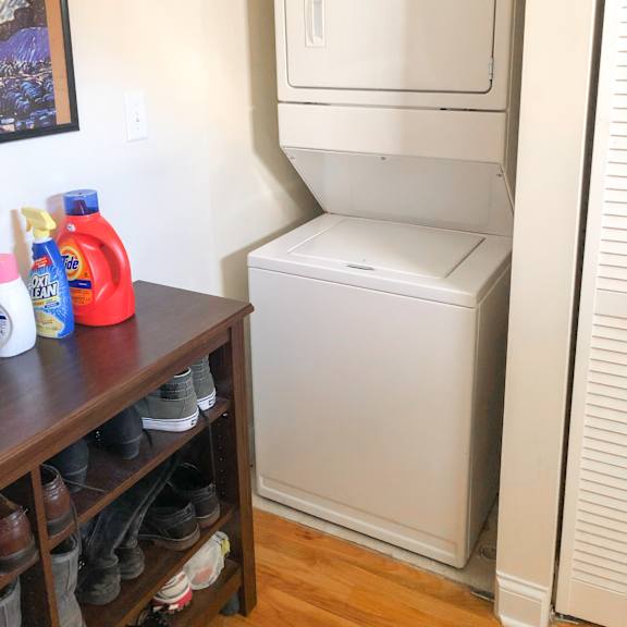 a white dishwasher is in a kitchen next to a wooden shelf with shoes on it.