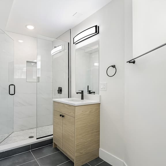 a modern bathroom with a walk-in shower and a wooden vanity.
