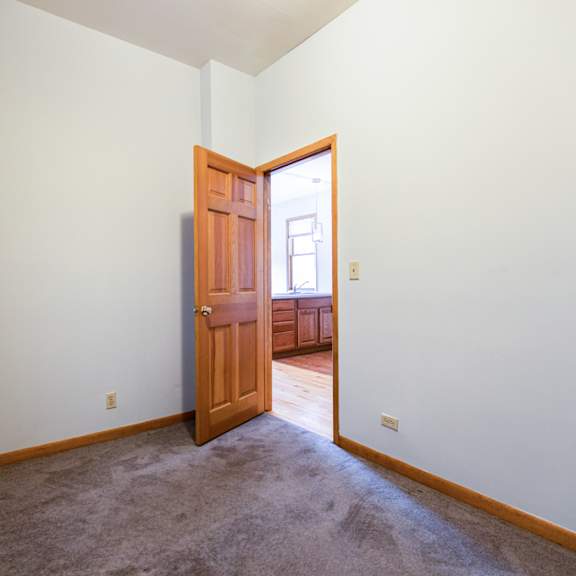 a room with a brown carpet and a wooden door.