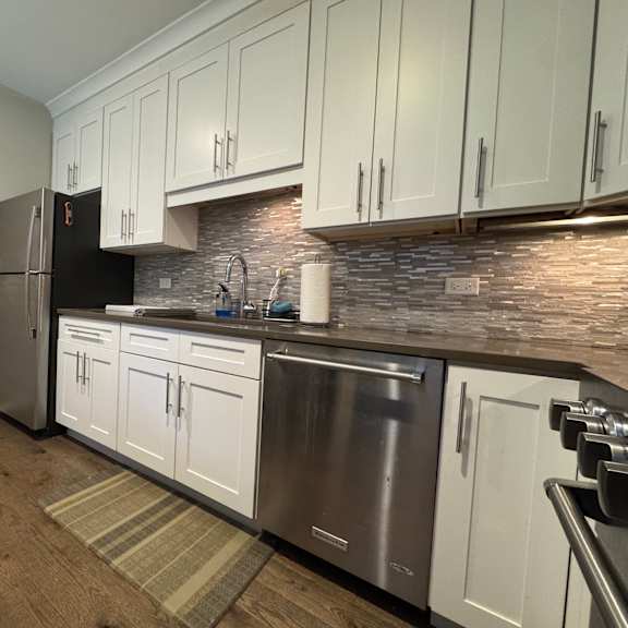 a kitchen with white cabinets and a stainless steel dishwasher.