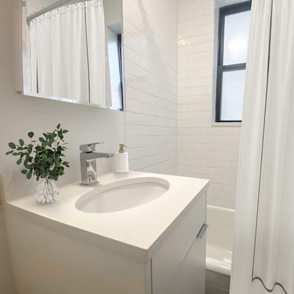 a white sink in a bathroom with a white curtain.