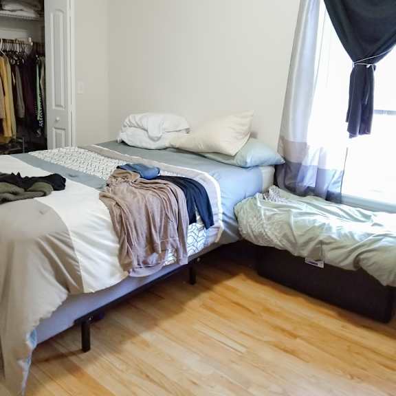 a bedroom with two beds and a closet with clothes on them