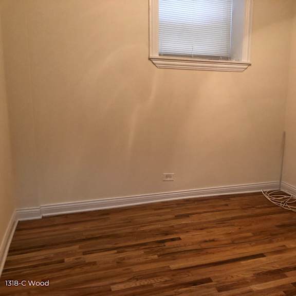 the corner of a room with wooden floors and a window