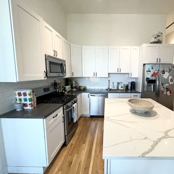 a kitchen with white cabinets and a marble counter top.