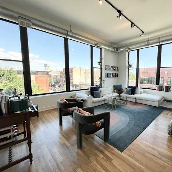 a living room with a white couch, a grey chair, and a wooden table.