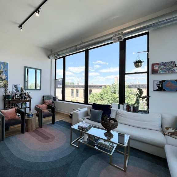 a living room with a white couch, a coffee table, and a large window.