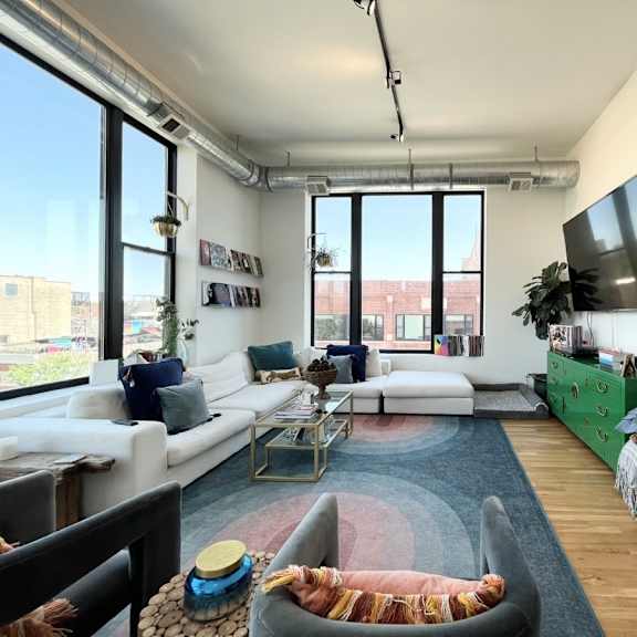 a living room with a white couch, a coffee table, and a tv on the wall.