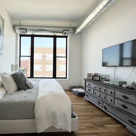 a bedroom with a large bed, a dresser, and a painting on the wall.