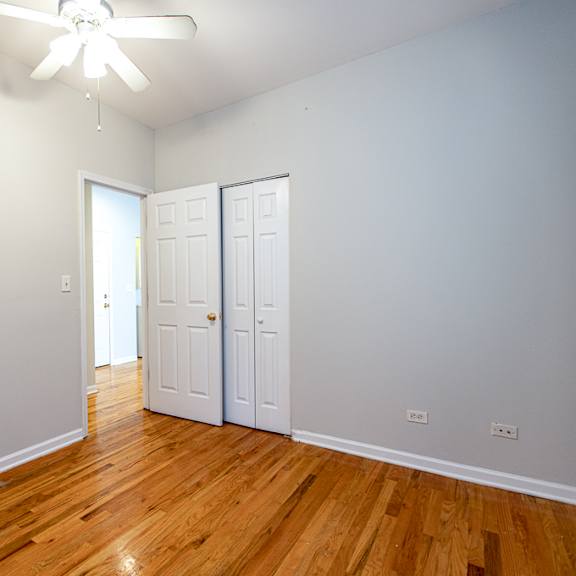 a room with a ceiling fan and wooden floors.