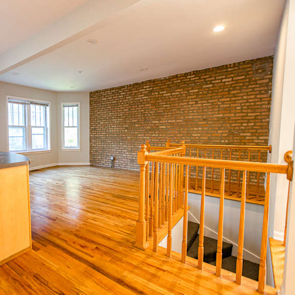 a room with a brick wall and wooden floors.