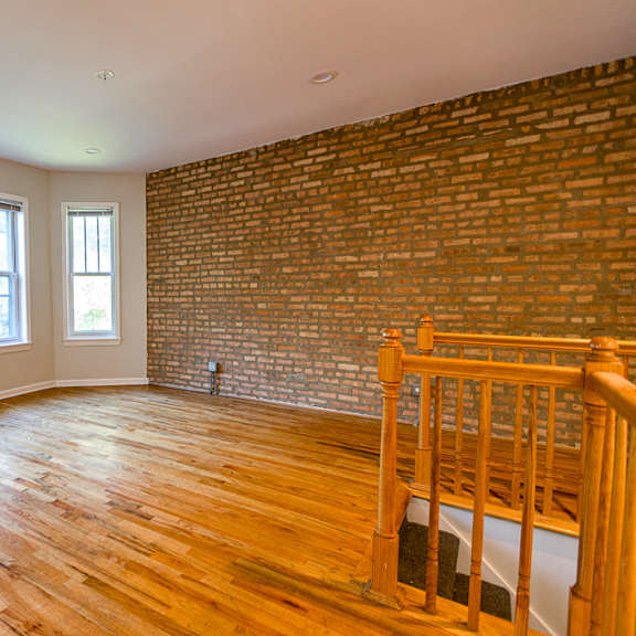 a room with wooden floors and a brick wall.
