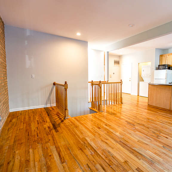 a kitchen with wooden floors and a brick wall.
