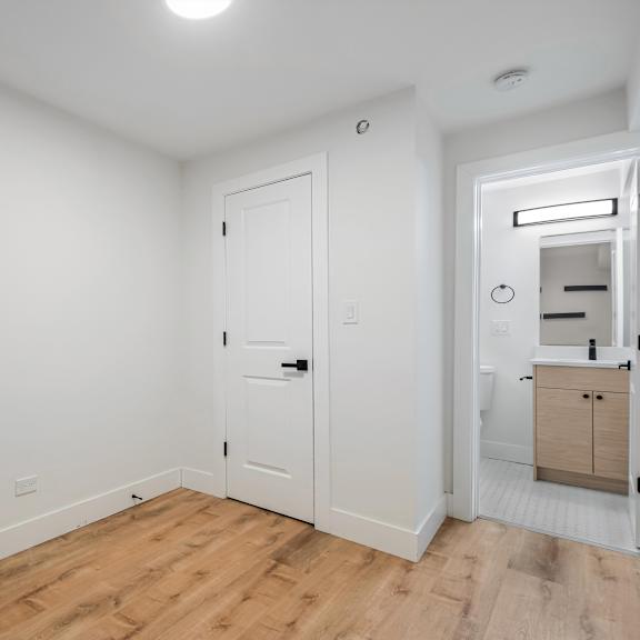 a white door is in a room with a wooden floor.