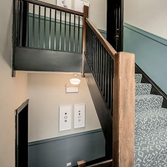 a staircase with a wooden handrail and a light switch on the wall.