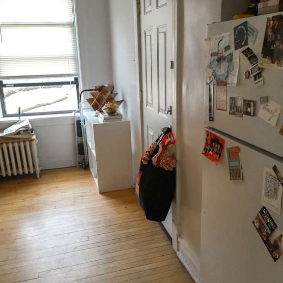 a kitchen with a white fridge covered in magnets and a door open.