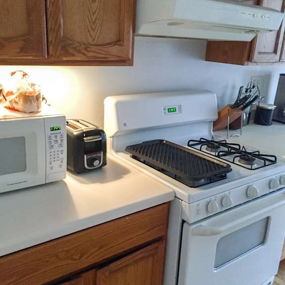 a white stove with a black stovetop is in a kitchen with wooden cabinets.
