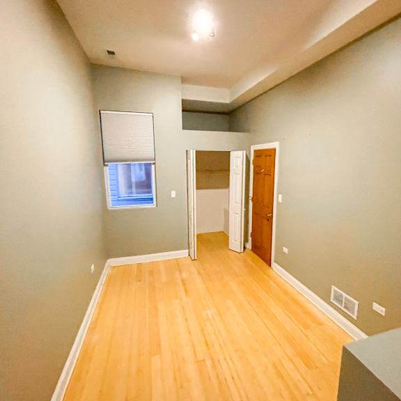 a room with wooden floors and a window with blinds.