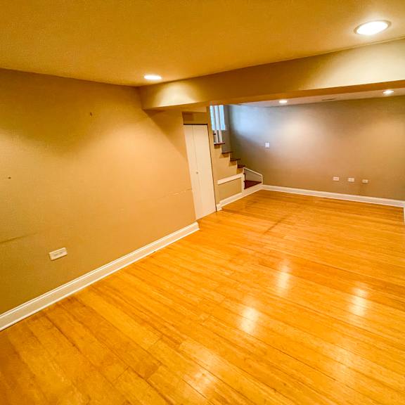 a room with wooden flooring and a staircase in the background.