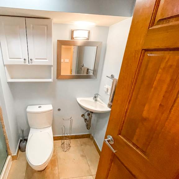 a bathroom with a toilet, sink, and mirror.