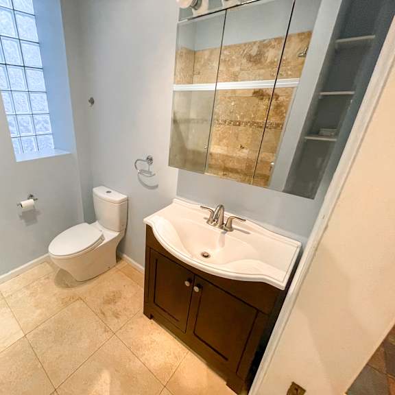 a bathroom with a toilet, sink, and mirror.