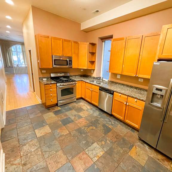 a kitchen with a refrigerator, microwave, oven, and cabinets.