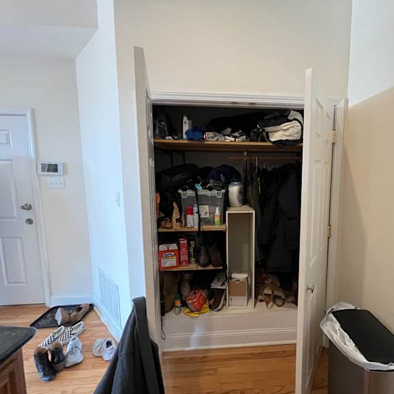 a small closet with a lot of clothes and shoes.