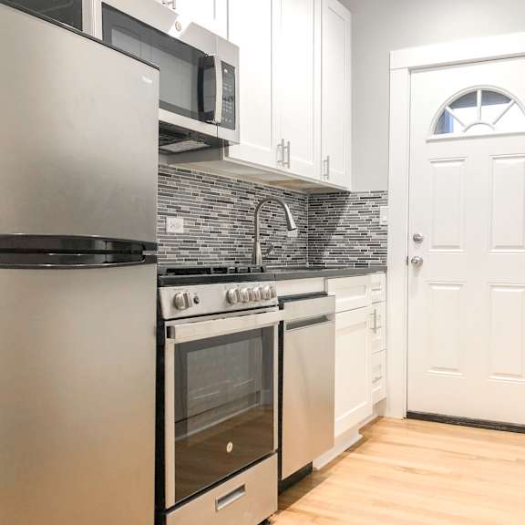 a kitchen with a white door and a black counter.