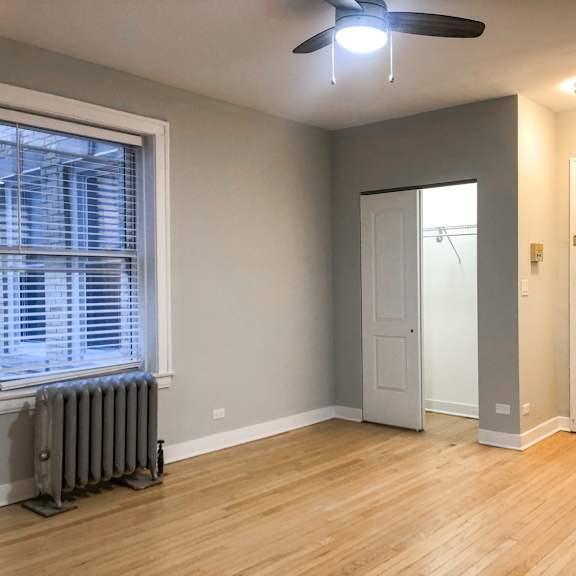 a room with a ceiling fan and a window with blinds.