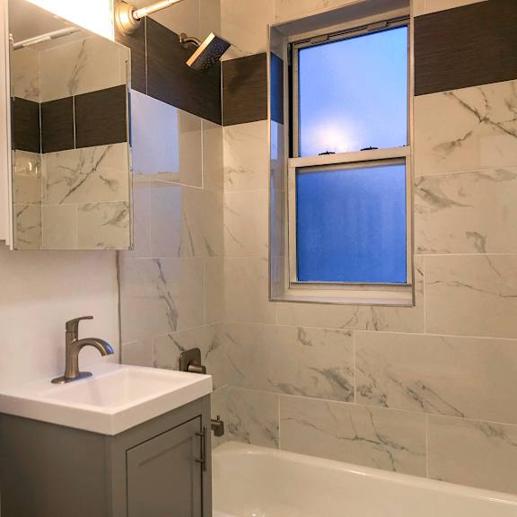 a bathroom with a marble tile wall and a window.