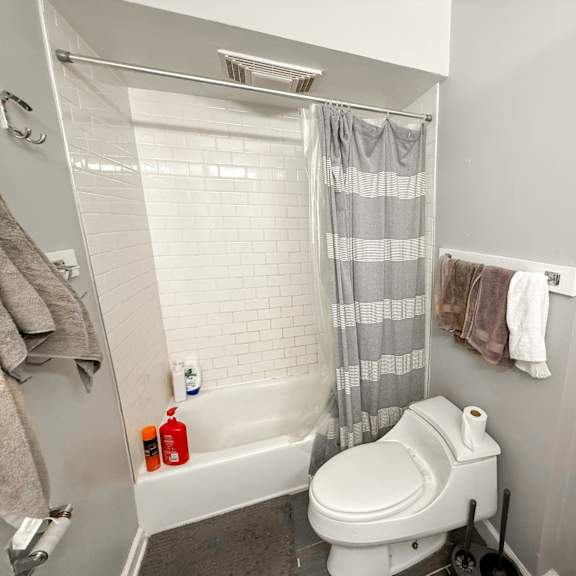 a white toilet in a bathroom with a shower curtain.