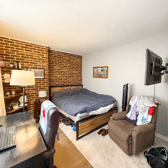 a bedroom with a bed, chair, and a television.