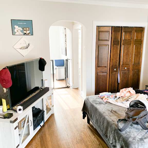 a bedroom with a bed, dresser, and a television.