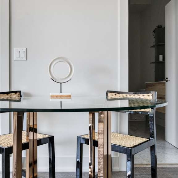 a round glass dining table with two chairs and a mirror 