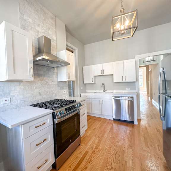 a modern kitchen with wooden floors and stainless steel appliances.