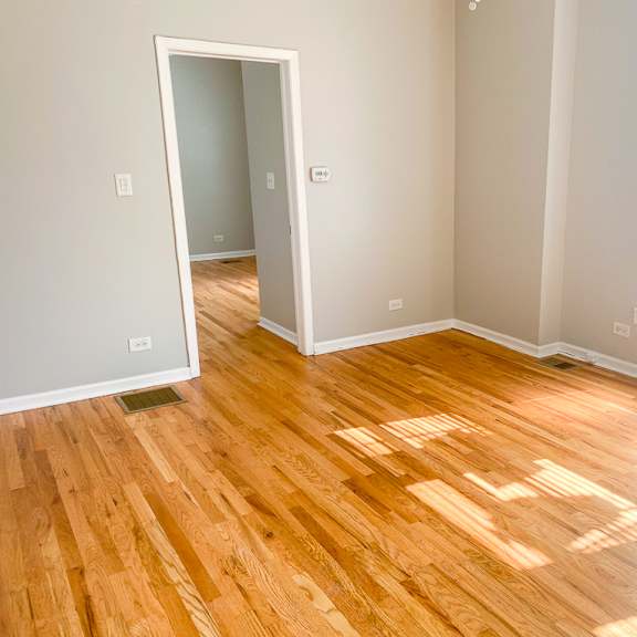 a room with wooden flooring and a window letting in sunlight.