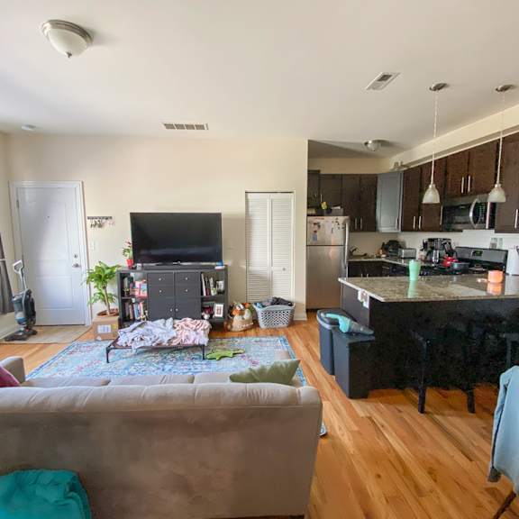 a living room with a couch and a kitchen in the background.