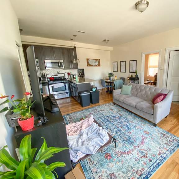 a living room with a rug on the floor and a staircase on the right.