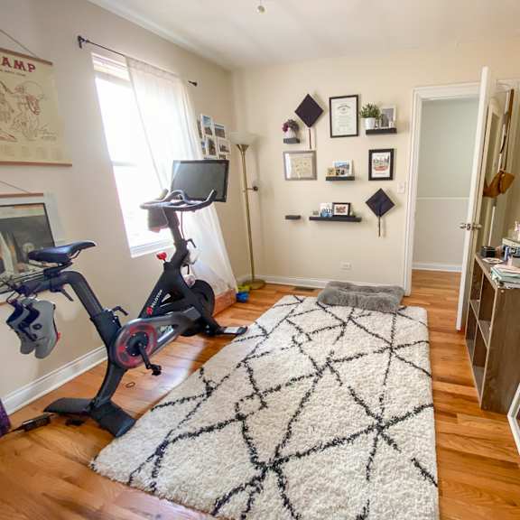 a room with a rug, a bike, a tv and a shelf.