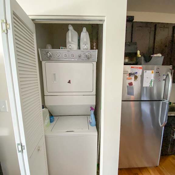 a white cabinet is open with a dishwasher and a washing machine inside.