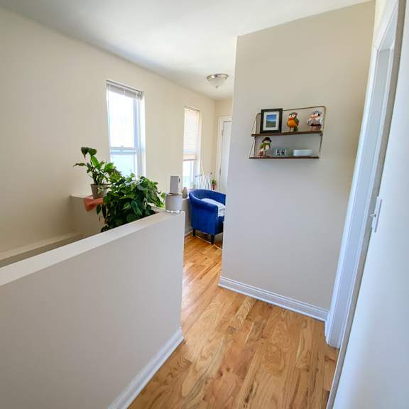 a room with a wooden floor and a white wall with a shelf on it.