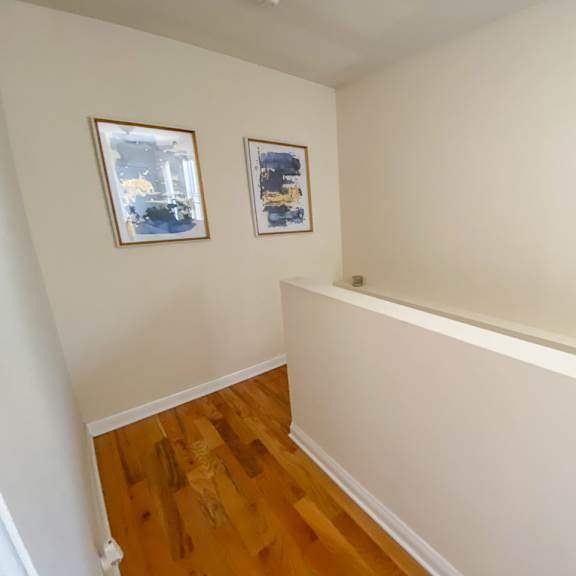 a room with wooden floors and two framed pictures on the wall.