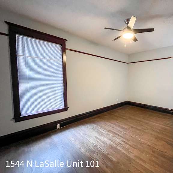 a room with a ceiling fan and a window with blinds.
