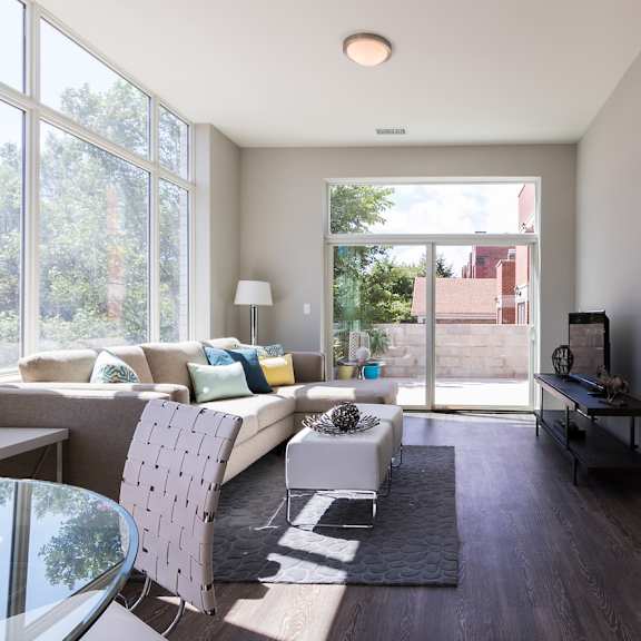 a modern living room with a glass table and a grey sofa.