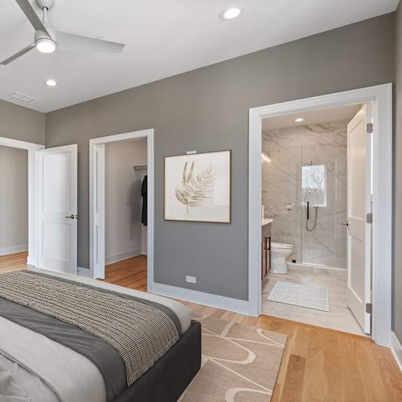 a bedroom with a large bed and a bathroom visible through the open door.