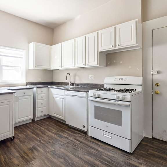 a white kitchen with wood floors and white appliances.
