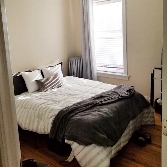 a bedroom with a bed, pillows, and a window.