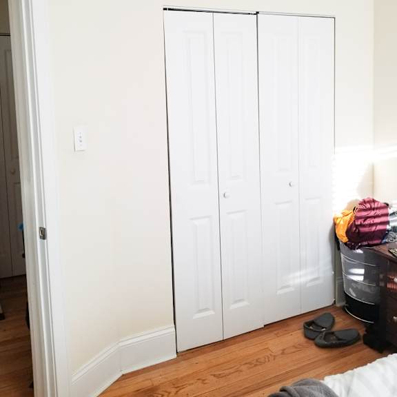 a white closet with a pair of black slippers in front of it.